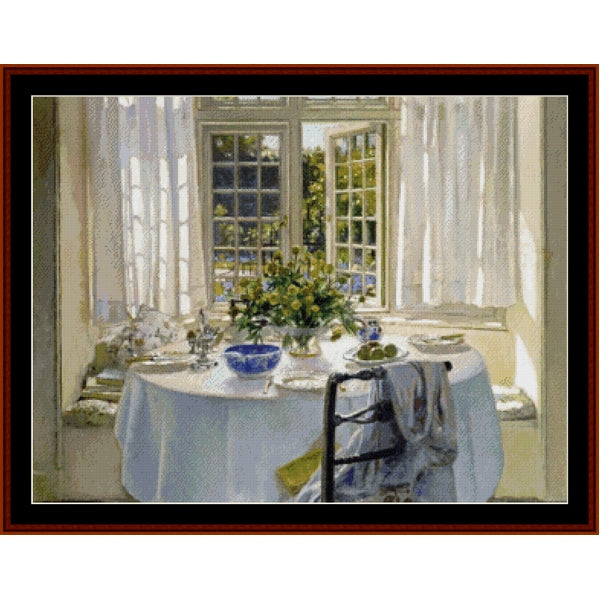 Counted Cross Stitch Pattern: Morning Room by Patrick W. Adam - Cross Stitch Collectibles - A framed art print depicting a bright sunlit dining nook with a round table set with a white tablecloth, blue bowl, and floral centerpiece, viewed through a dark reddish-brown frame.
