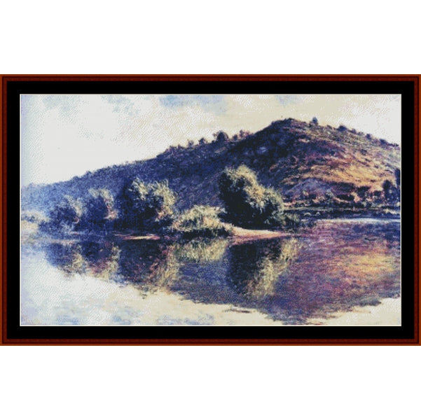 Counted Cross Stitch Pattern – Seine at Port Villez by Claude Monet - Cross Stitch Collectibles - A framed landscape painting depicting a hillside with trees reflected in calm water