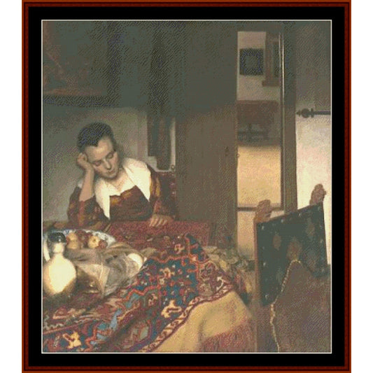 Counted Cross Stitch Pattern by Cross Stitch Collectibles - Woman at a table with a patterned cloth, holding a book, in a dimly lit room.