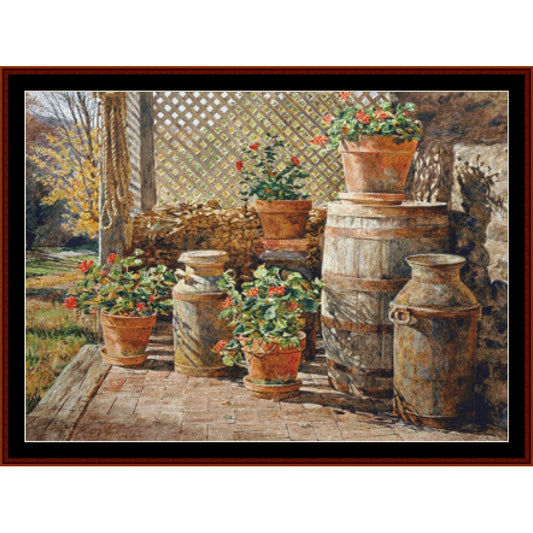 Counted Cross Stitch Pattern – October Shadow, Americana - Cross Stitch Collectibles - A framed art print depicting a rustic outdoor patio scene with potted red flowers, terracotta pots, wooden barrels, and vintage metal milk cans on a brick floor.