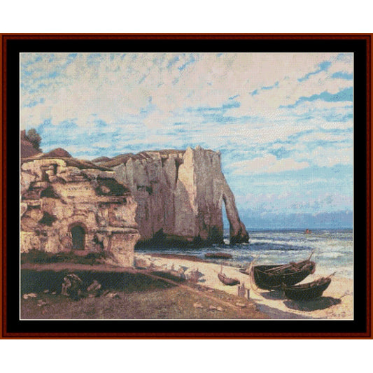 Counted Cross Stitch Pattern – Cliffs at Etretat by Gustave Courbet - Cross Stitch Collectibles - A framed landscape painting depicting a coastal scene with tall white cliffs, a sandy shore, small boats, and a blue sky with clouds