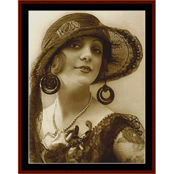 Vintage-style Counted Cross Stitch Pattern by Cross Stitch Collectibles of a woman with a large hat and hoop earrings, framed in brown.