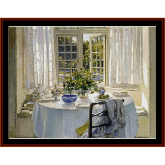Counted Cross Stitch Pattern: Morning Room by Patrick W. Adam - Cross Stitch Collectibles - A framed art print depicting a bright sunlit dining nook with a round table set with a white tablecloth, blue bowl, and floral centerpiece, viewed through a dark reddish-brown frame.