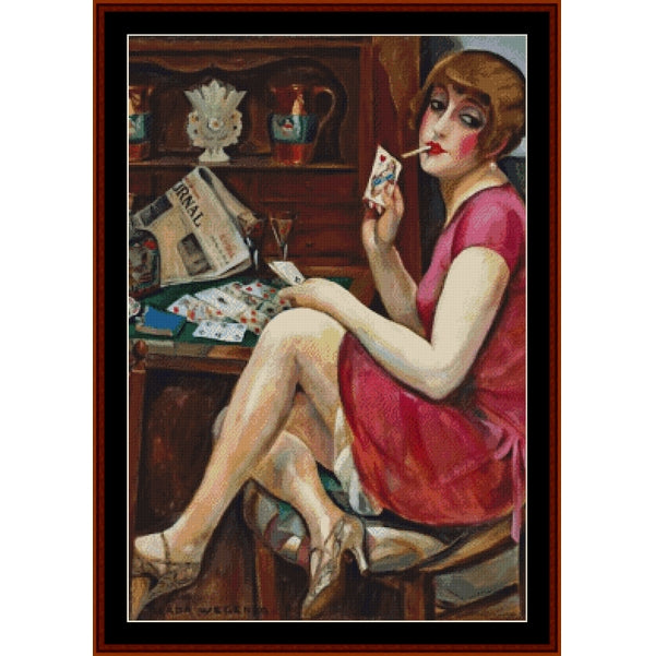 Counted Cross Stitch Pattern – Queen of Hearts by Gerda Wegener - Cross Stitch Collectibles - A framed art print depicting a 1920s flapper woman in a pink dress sitting at a table with cards, holding a cigarette